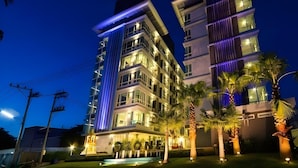 Un hôtel à plusieurs étages, doté de balcons illuminés et d’un hall d’entrée bien éclairé.