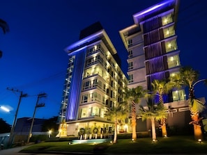 A multi-story hotel with illuminated balconies and a well-lit entrance area. - The Ozone Boutique Hotel (Udon Thani)