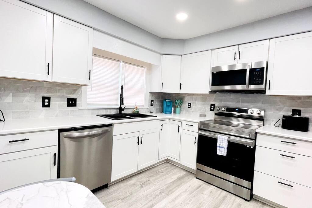 A modern kitchen with white cabinets, stainless steel appliances, and a dishwasher.