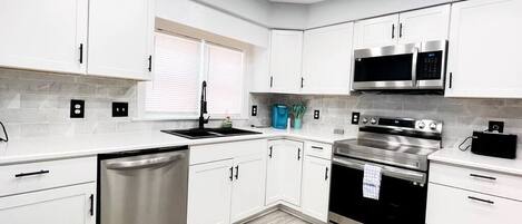 A modern kitchen with white cabinets, stainless steel appliances, and a dishwasher.