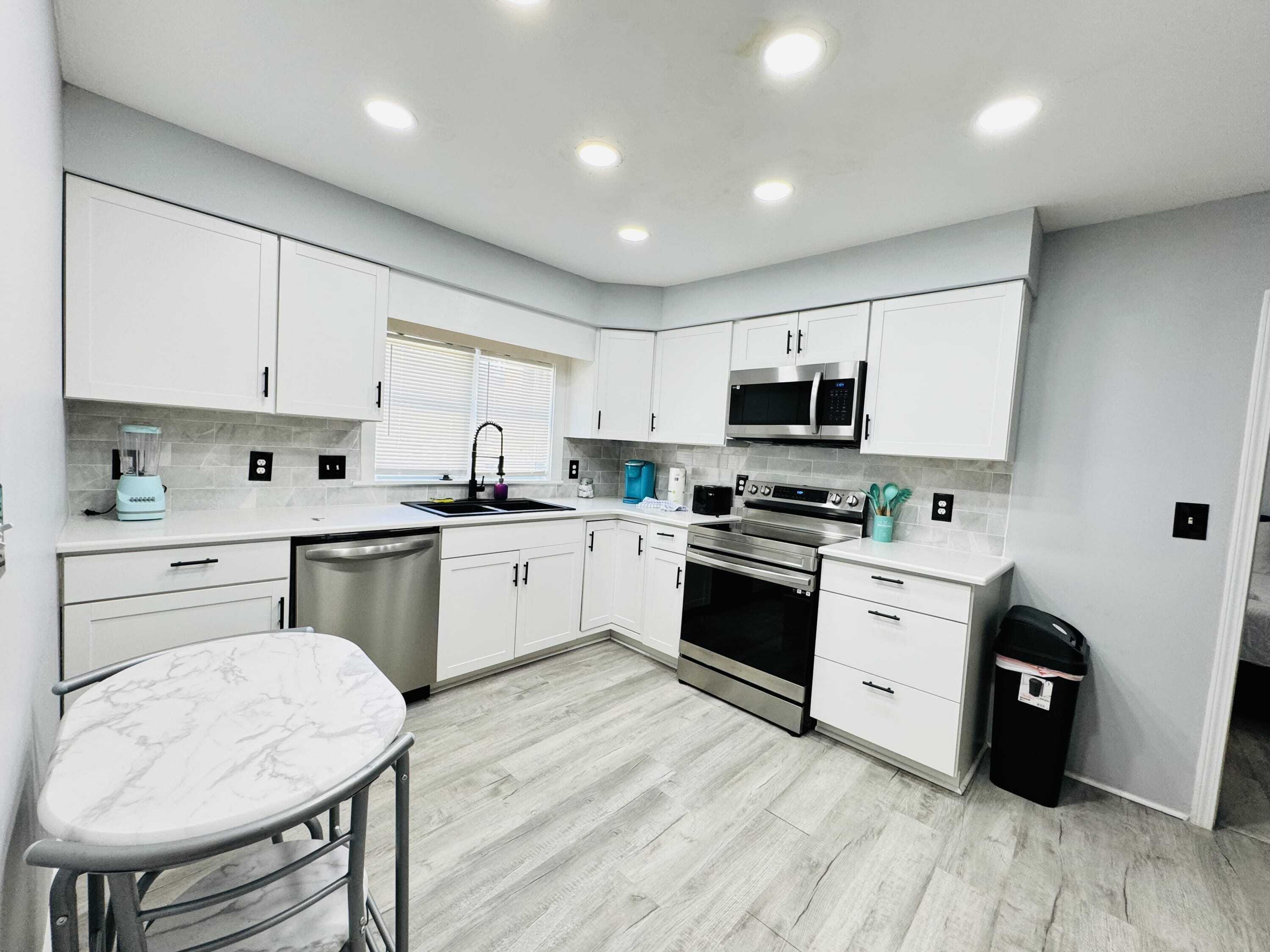 A modern kitchen with white cabinets, a stainless steel dishwasher, a built-in oven, and a microwave.