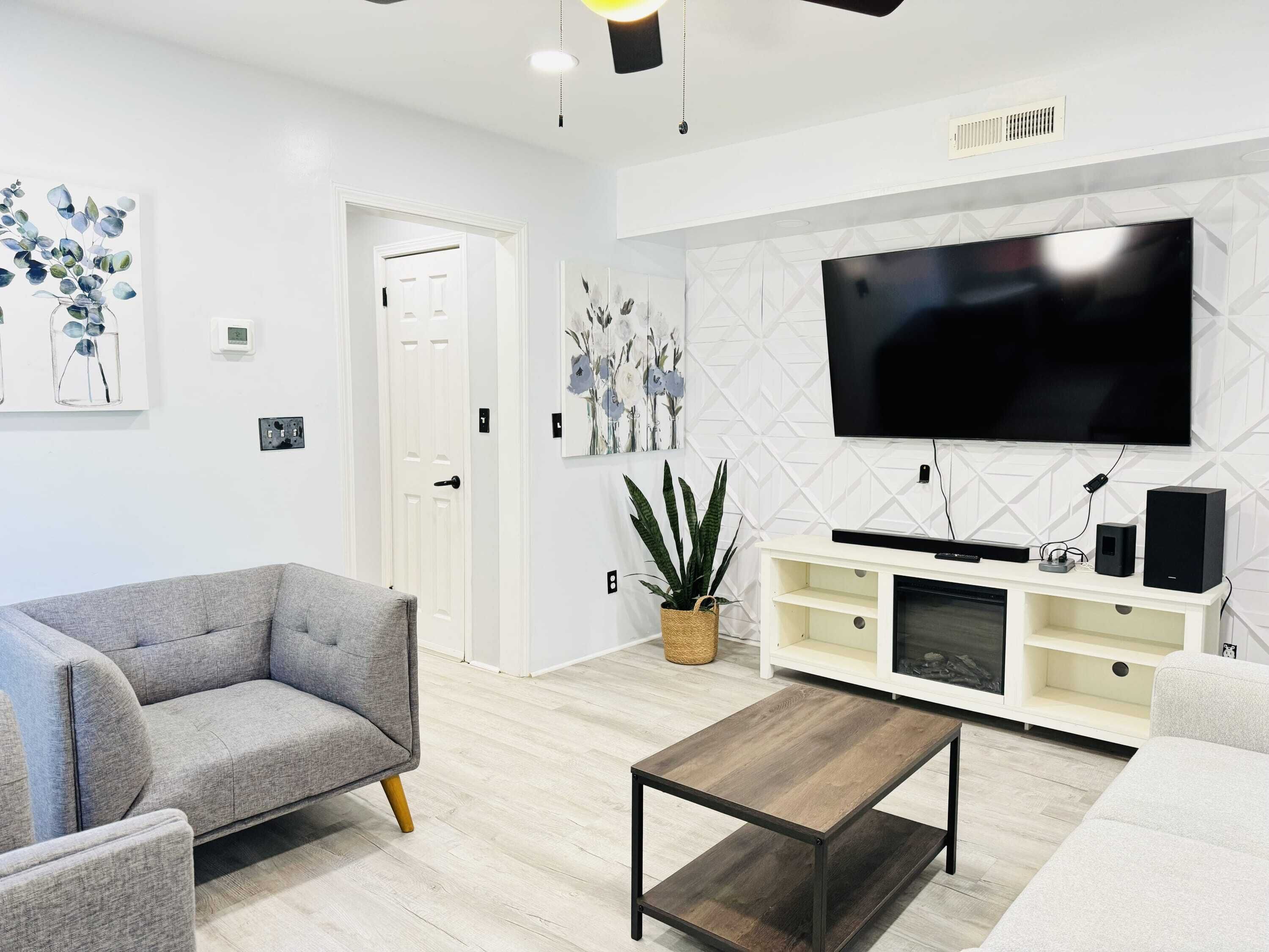 A modern living room with a flat-screen TV, a sofa, a coffee table, and a plant.
