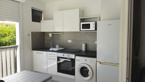 A compact kitchen with a microwave, oven, and washing machine.