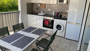 A compact kitchen with a microwave, oven, washing machine, and refrigerator.
