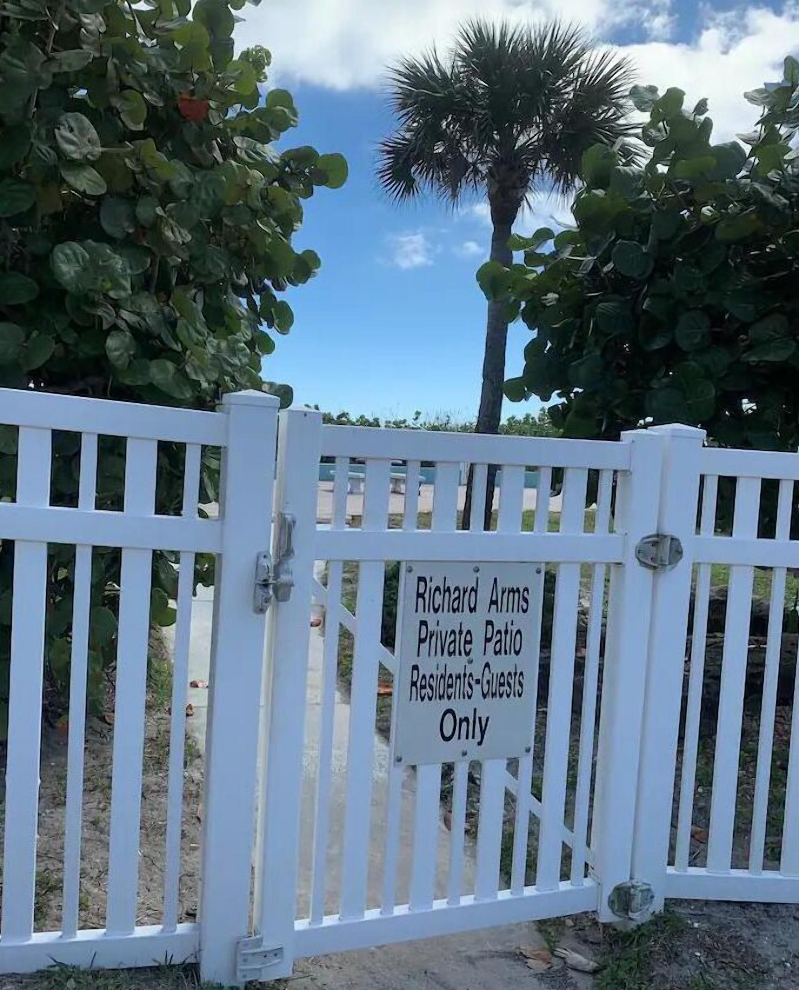 A white gate with a sign that reads "Richard Arms Private Patio Residents-Guests Only".