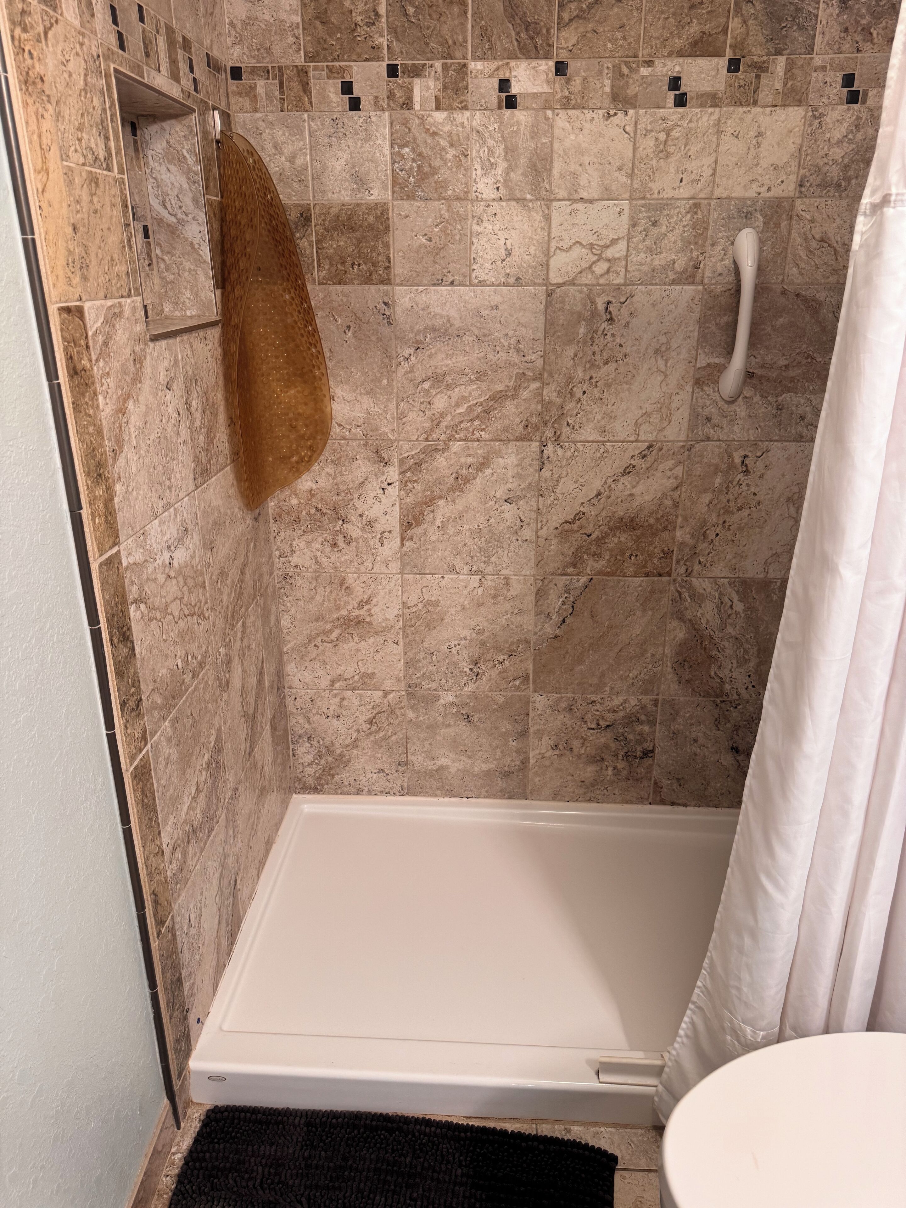 Un espacio de ducha con una bañera blanca, una toalla colgada en un perchero y un cortinón de ducha.