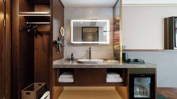 A modern bathroom with a vanity, mirror, and built-in refrigerator.