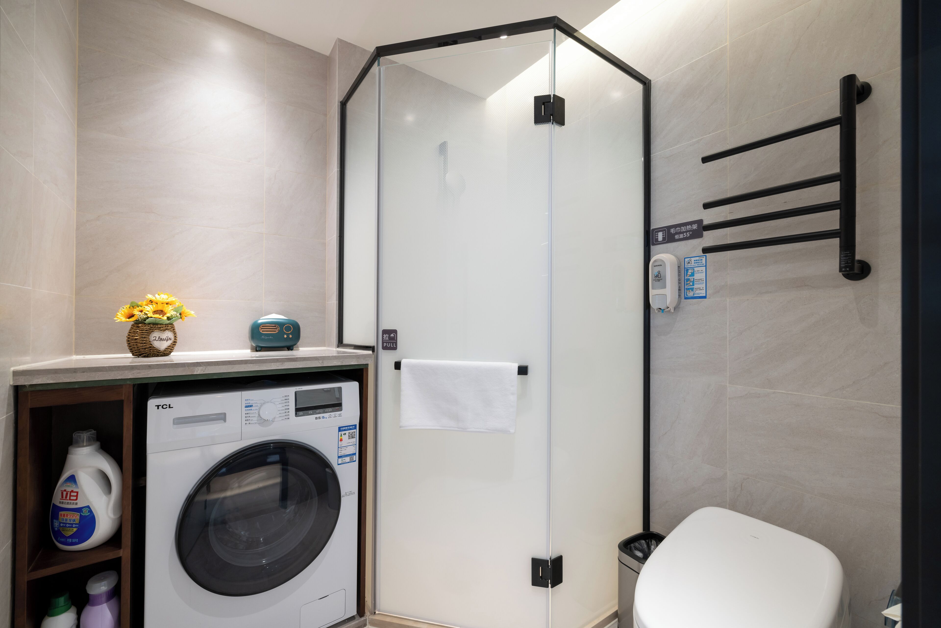 Een moderne badkamer met een douchecabine van glas, een wasmachine en een toilet.