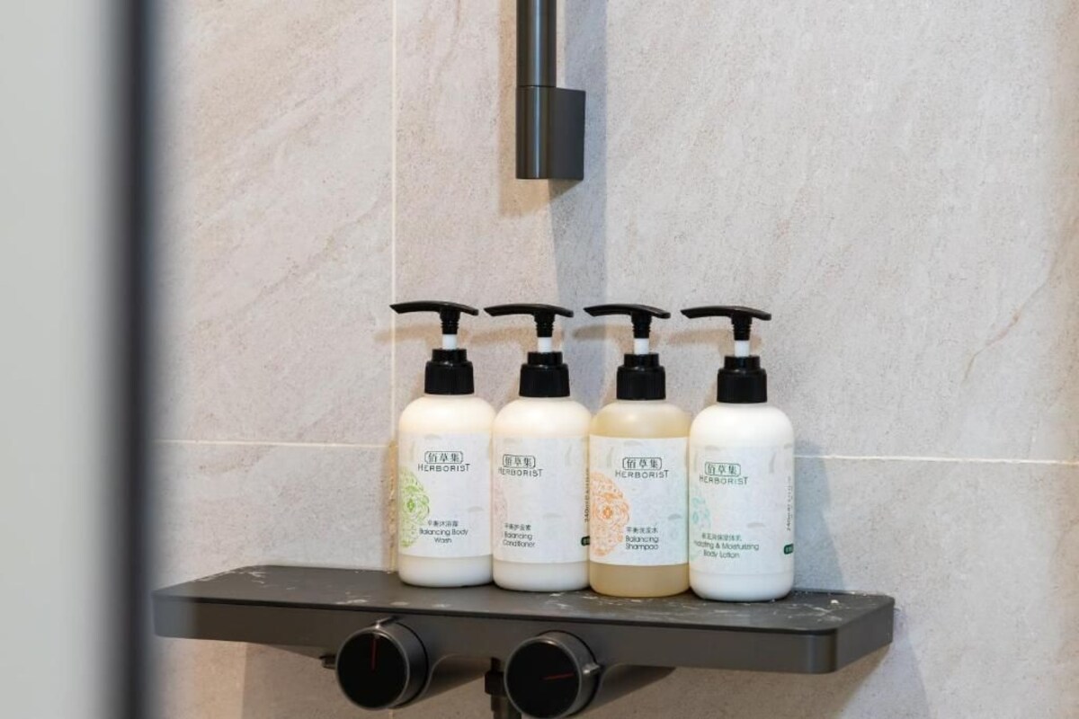 A shelf with four bottles of body care products in a bathroom.