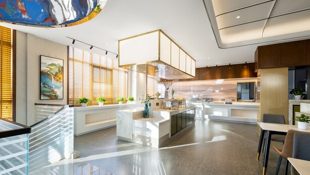 Eine moderne Hotelhalle mit einer zentralen Rezeption, einer Sitzecke und einer Treppe.
