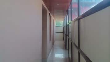 Um corredor com piso de azulejos, teto de madeira e paredes de vidro.