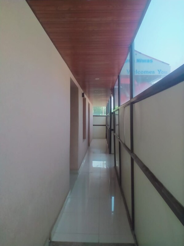 A corridor with a tiled floor, wooden ceiling, and glass walls.