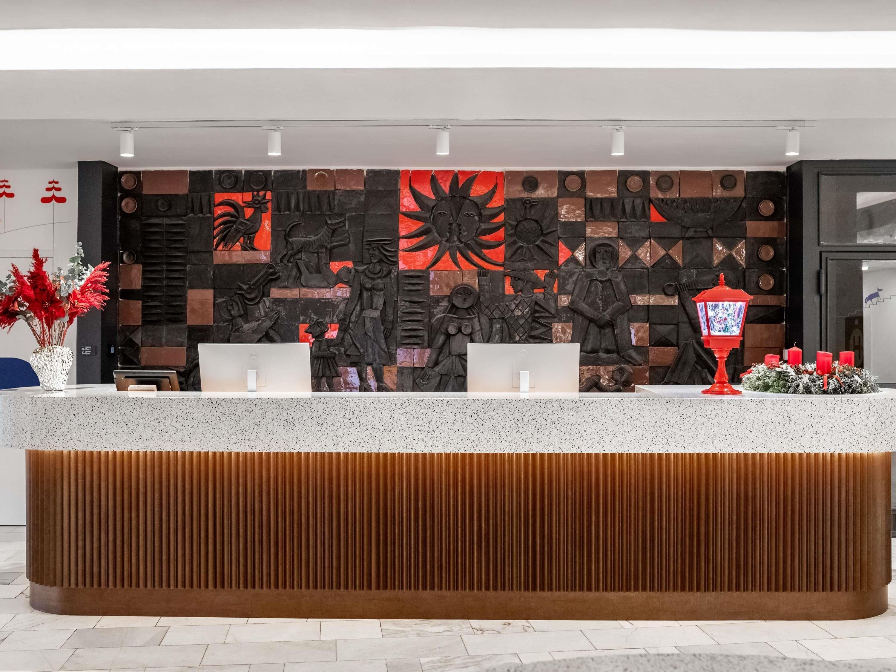 Una recepción con diseño moderno, que incluye un panel de madera y una pared decorativa con esculturas en relieve.