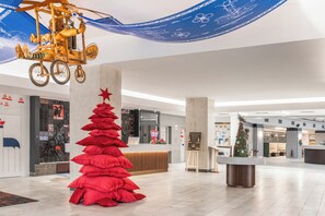 Un hall d’entrée moderne avec un comptoir d’accueil, un sapin de Noël et une décoration suspendue originale.