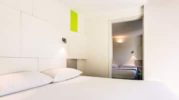A modern hotel room with a bed, a bedside table, and a small desk.