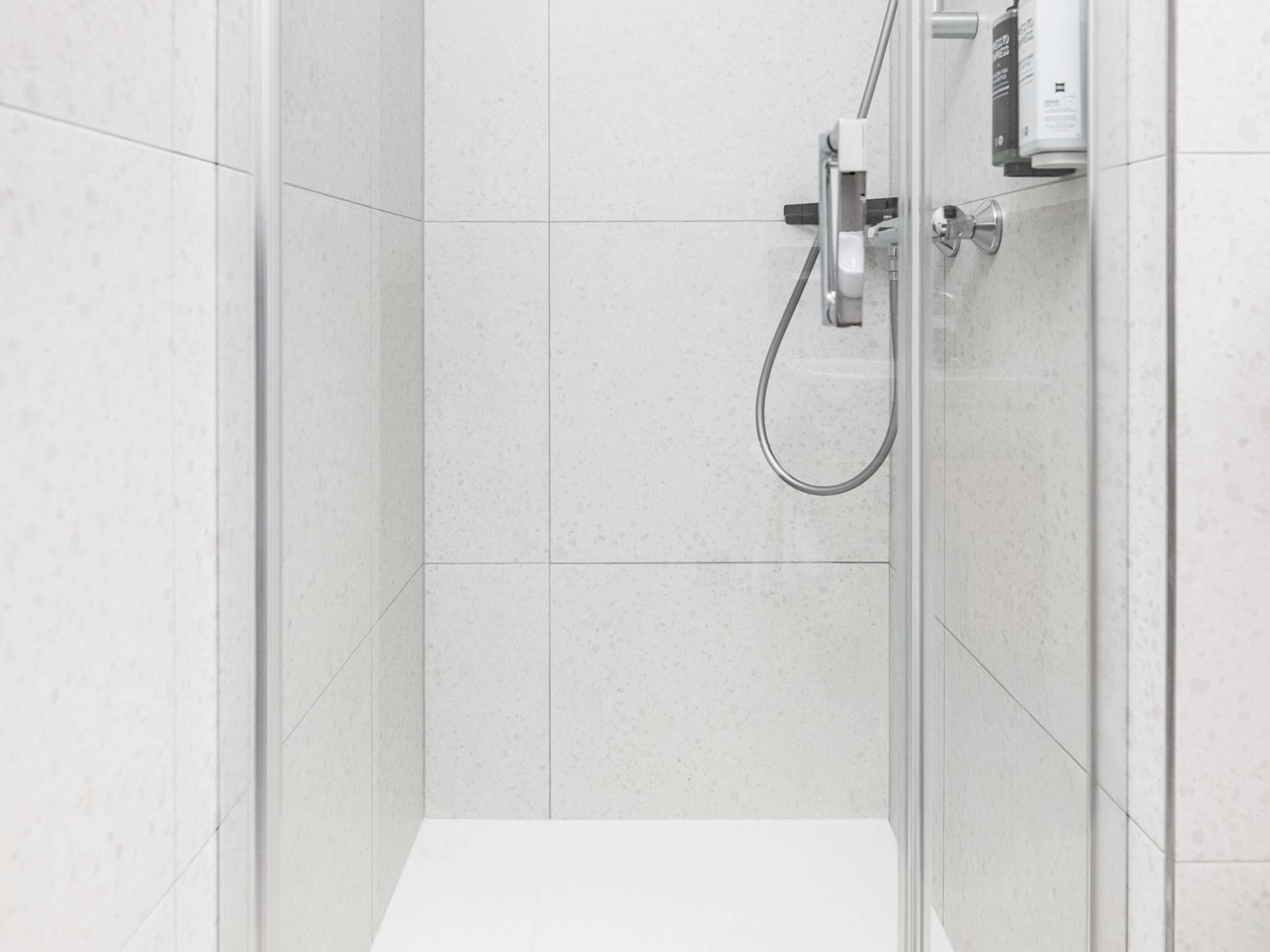 A modern shower with a handheld showerhead and a control panel.