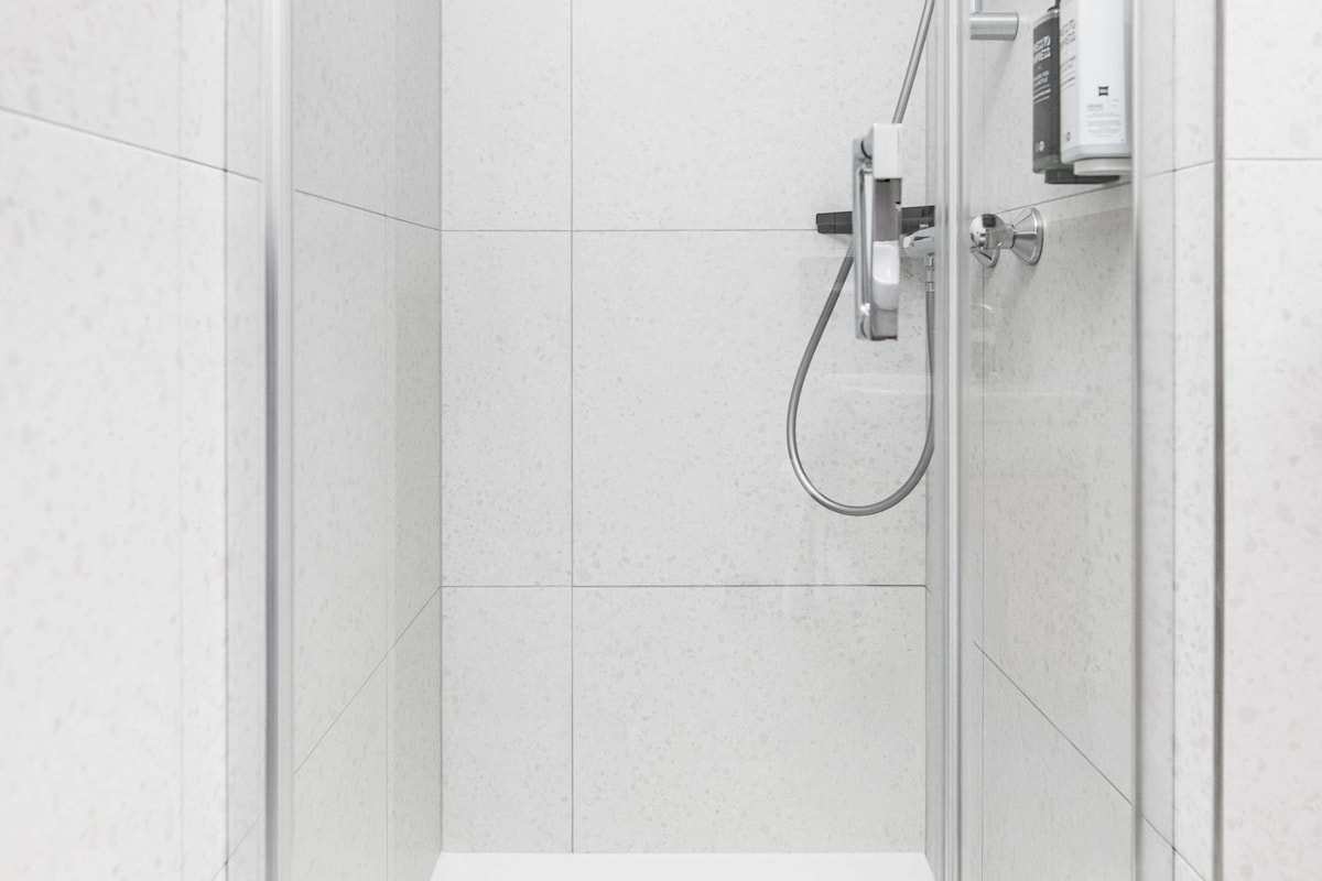 A modern shower with a handheld showerhead and a control panel.