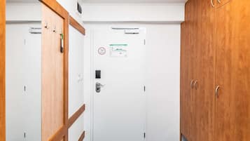 Een gang met een witte deur, een houten garderobe en een blauw tapijt.