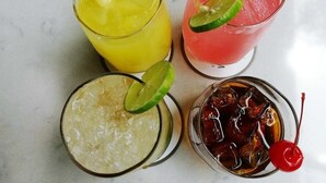 Quatro bebidas diferentes, cada uma decorada com uma fatia de limão.