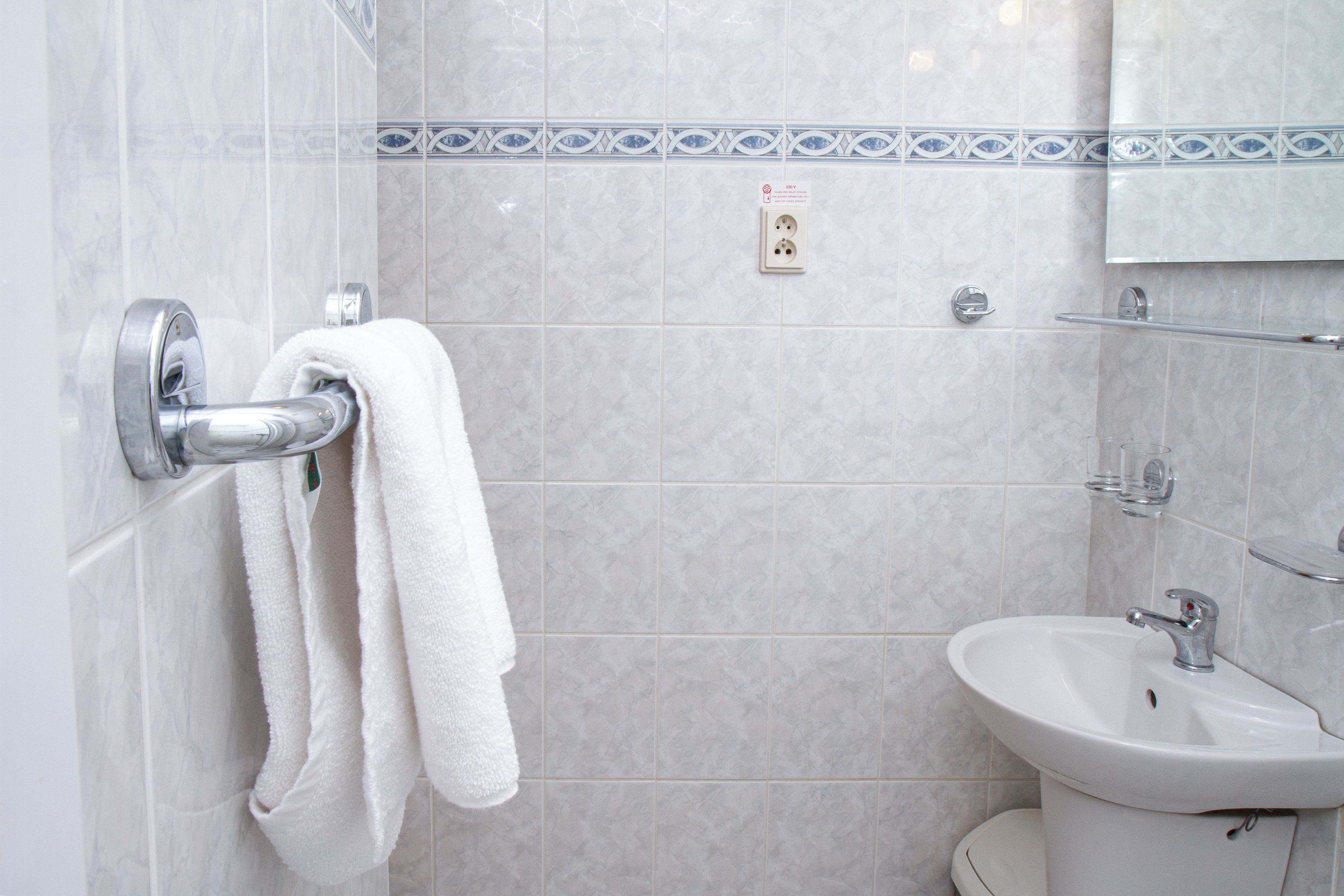 A bathroom with a white sink, a towel rack with two towels, and a mirror above the sink.