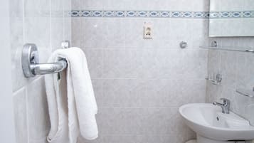 A bathroom with a white sink, a towel rack with two towels, and a mirror above the sink.