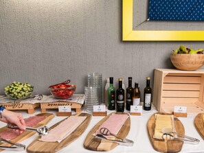 A food and drink display with various cheeses, cured meats, and bottles of wine.