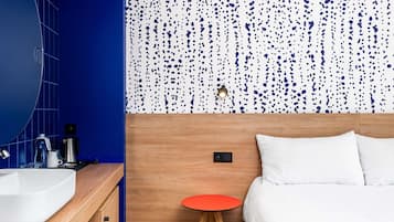 Une salle de bain moderne avec un grand miroir, un lavabo blanc et un mur recouvert de carreaux bleus.