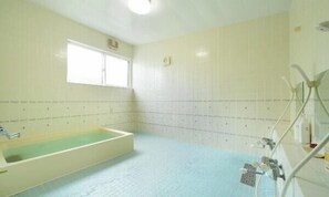 Een badkamer met een bad, een raam en een douche.