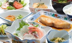 Diverse gerechten, waaronder een kom soep, een bord zalm en een kom rijst.