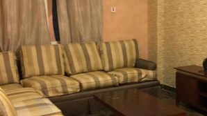 A living room with a sofa, a coffee table, and a small side table. - Al Wouroud Serviced Appartment (Khamis Mushait)