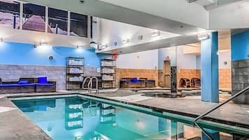 An indoor swimming pool with lounge areas, a changing room, and a staircase.