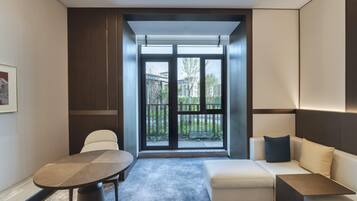 A modern living room with a sofa, a round table, and a large window offering a view of a residential area.