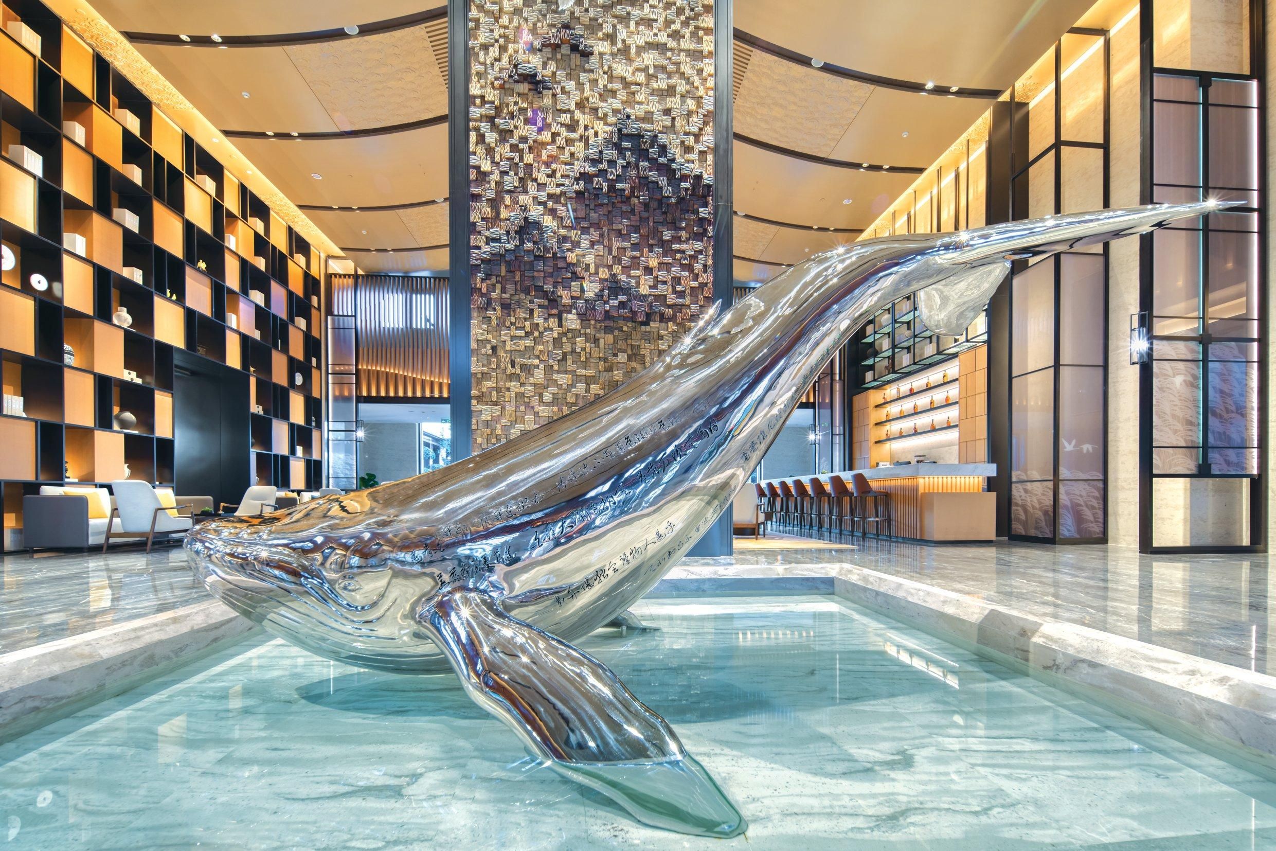 A modern lobby with a large glass sculpture, a patterned wall, and a reception desk.
