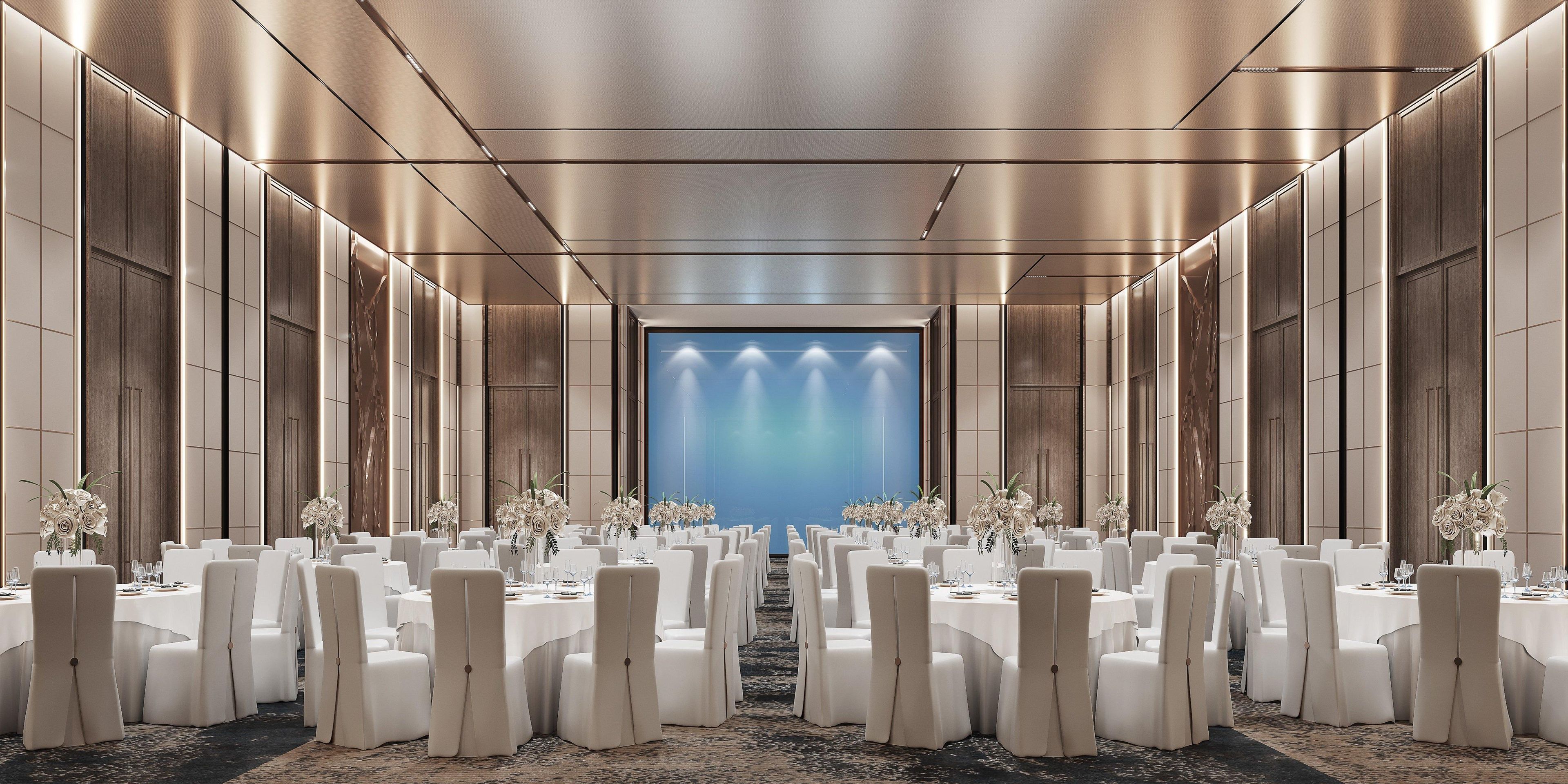A long banquet hall with rows of round tables, each set with white tablecloths and chairs, and floral centerpieces.
