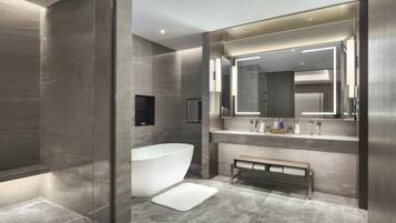 A modern bathroom with a freestanding bathtub, a bench, and a large mirror above the sink.