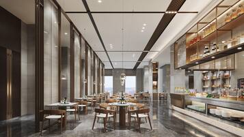 A modern dining area with multiple tables and chairs, a buffet counter with food displays, and large windows offering a city view.