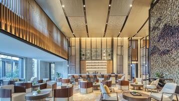 A spacious lobby with modern seating, a bar area, and a stone wall.