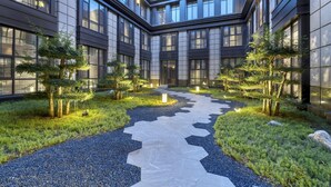 A modern building with a central pathway, surrounded by trees and gravel. - Voco Xiong An (Baoding)