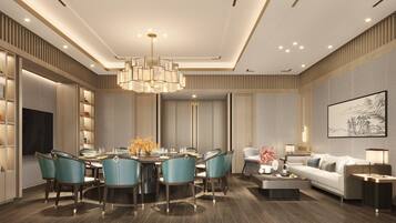 A modern dining area with a round table, teal chairs, and a chandelier.