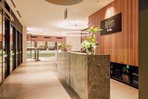 A reception area with a modern design, featuring a reception desk, a sign with the name 'Péem Yarra Valley', and a decorative vase with flowers. - Re'em Yarra Valley (Melbourne)