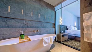 Une salle de bain moderne avec une baignoire sur pieds, un plateau en bois avec une bouteille, et une serviette accrochée sur le côté.