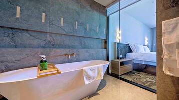A modern bathroom with a freestanding bathtub, a wooden tray with a bottle, and a towel hanging on the side.