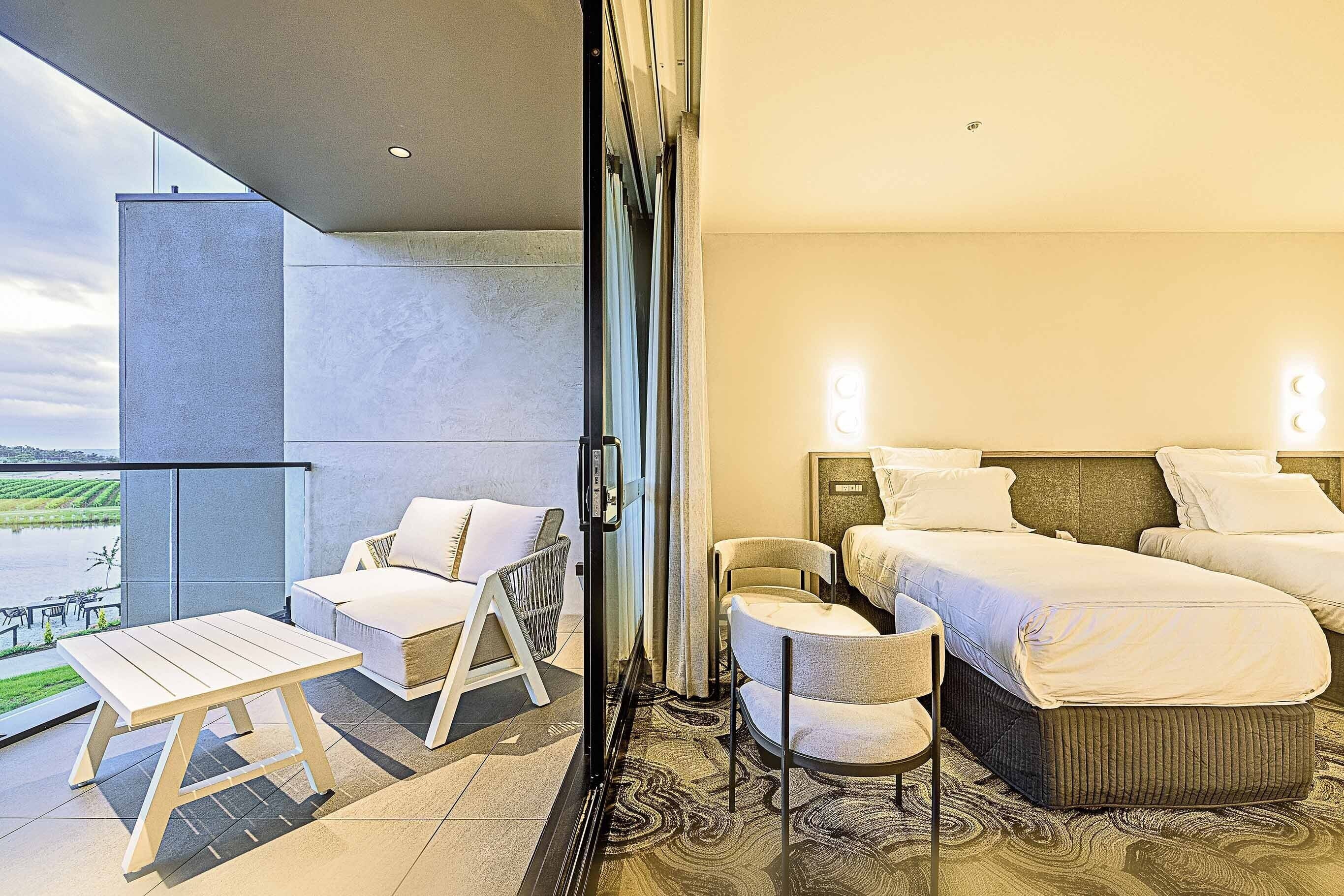 Habitación de hotel con balcón, una cama, una silla y una pequeña mesa.