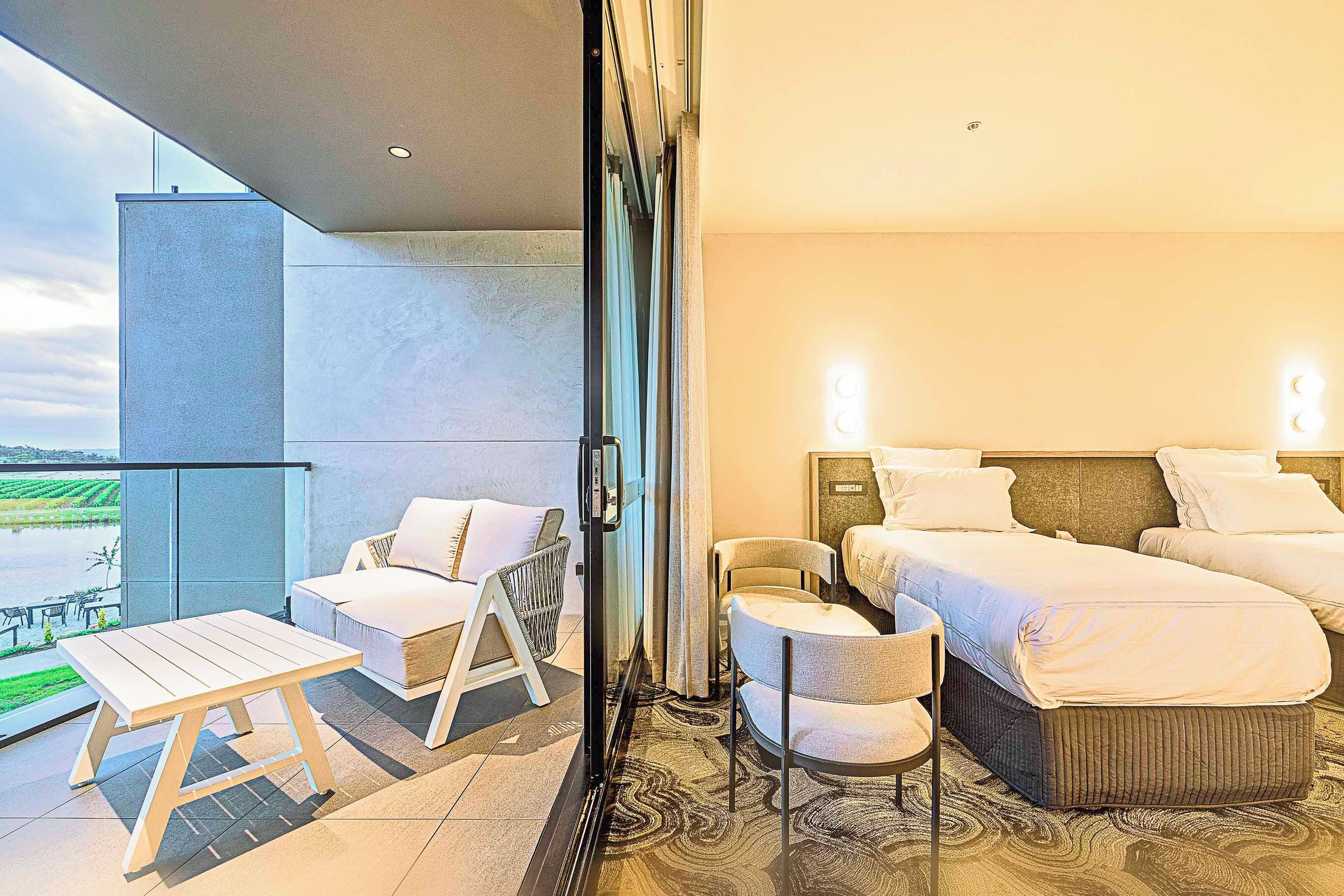 A hotel room with a balcony, a bed, a chair, and a table.