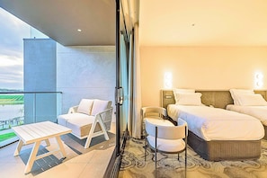 A hotel room with a balcony, a bed, a chair, and a table.