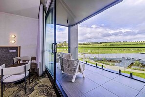 A modern hotel room with a balcony, a seating area with chairs, and a view of a green landscape. - Re'em Yarra Valley (Melbourne)