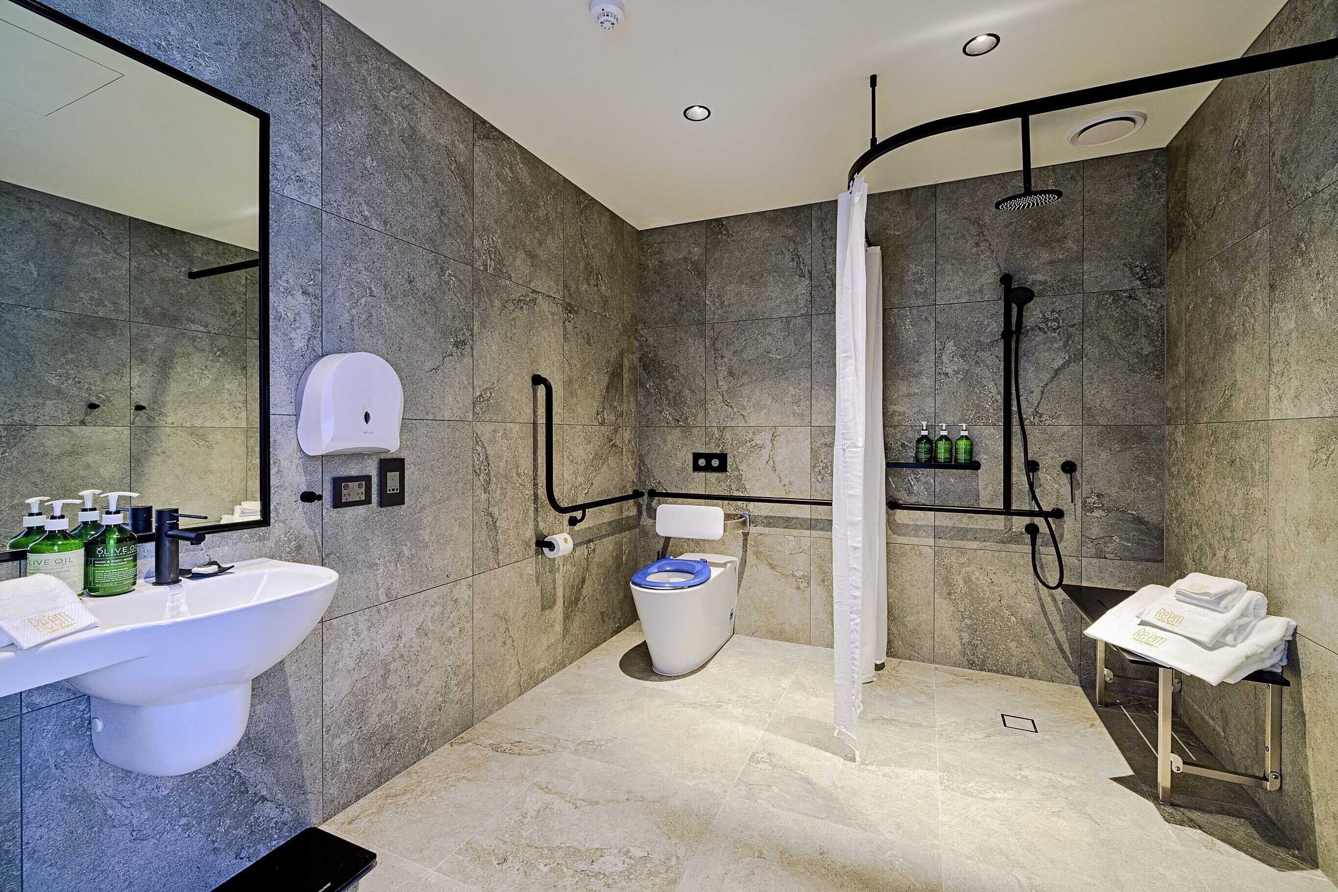 Un baño moderno con un lavabo grande, inodoro y zona de ducha.