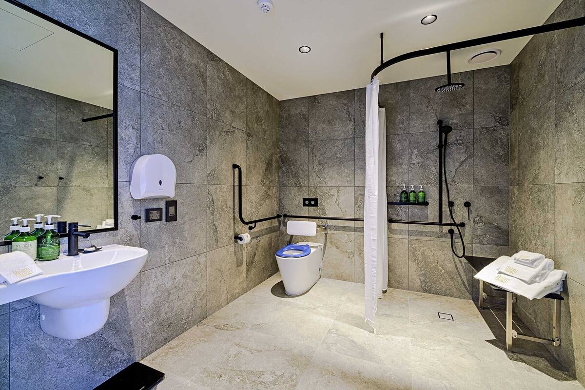 A modern bathroom with a large sink, toilet, and shower area.