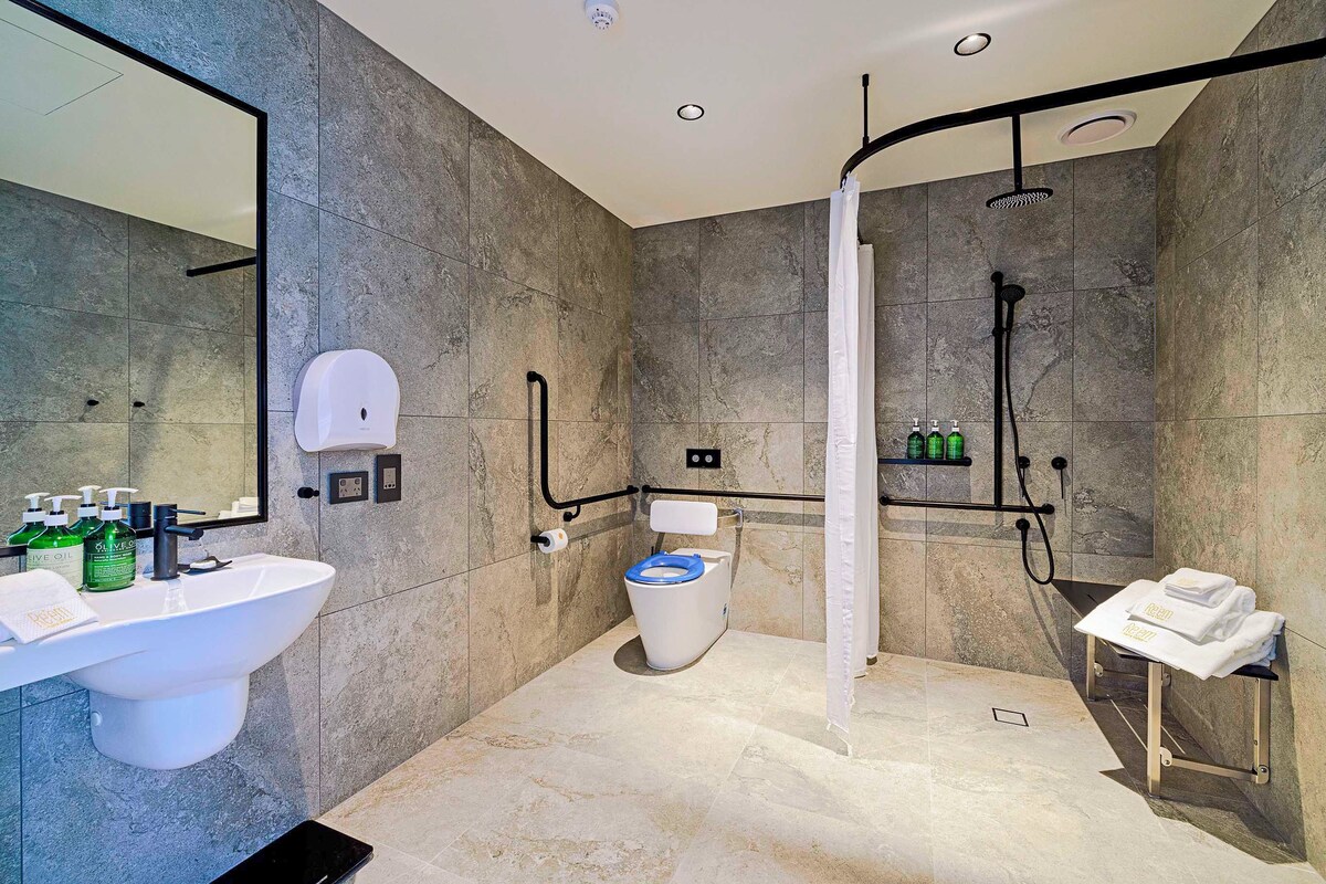 A modern bathroom with a large sink, toilet, and shower area.