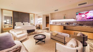 Une chambre d’hôtel comprenant un lit, un canapé, une table basse, une télévision et un coin cuisine.